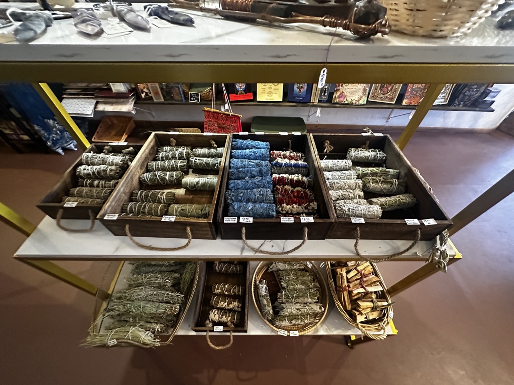 Wooden boxes of bundled sage, rosemary, eucalyptus, and palo santo on a cart