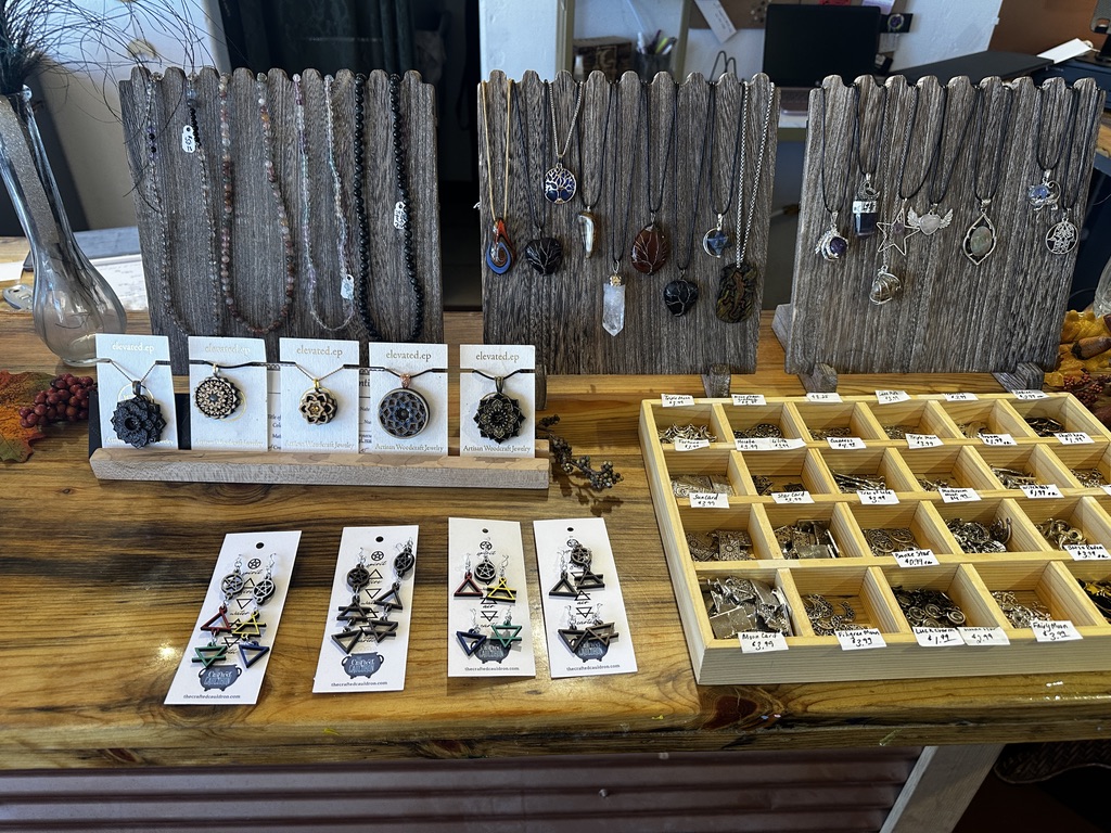 Pendant necklaces and earrings displayed on weathered wood stands