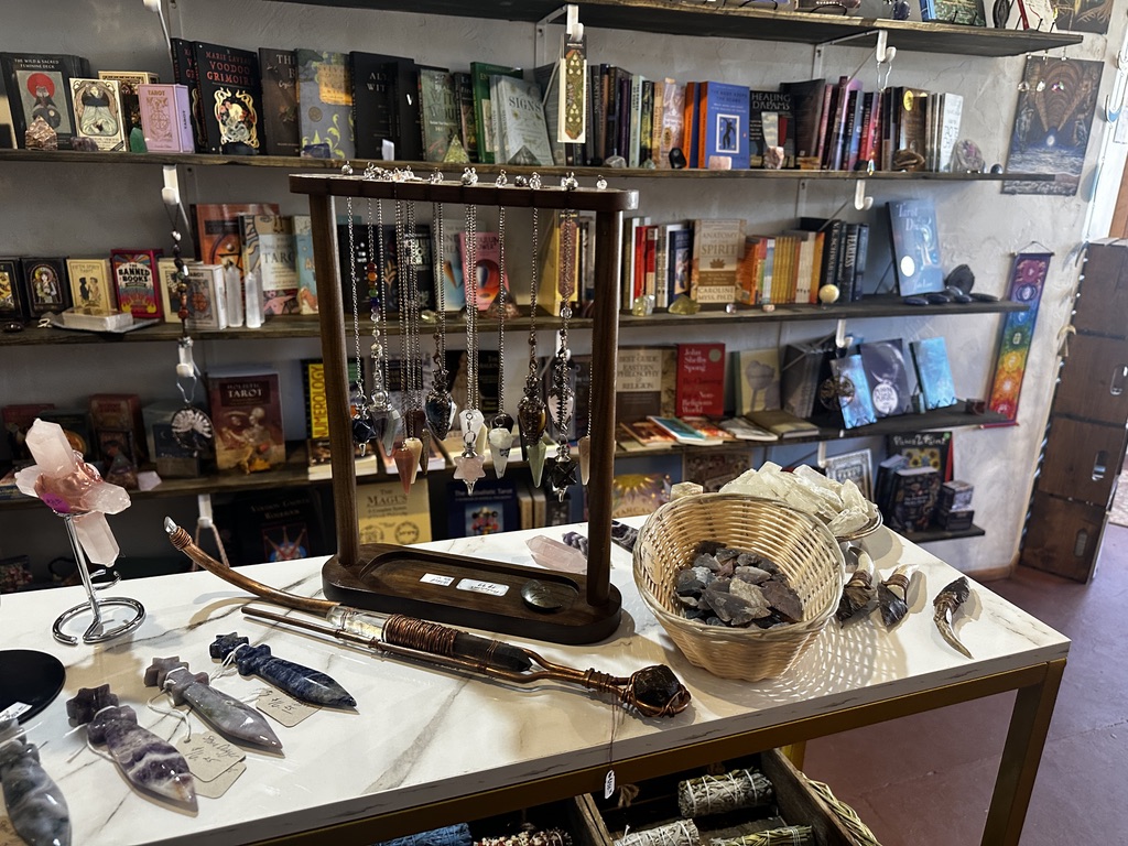 Crystal pendulums on a wooden stand in front of shelves of books