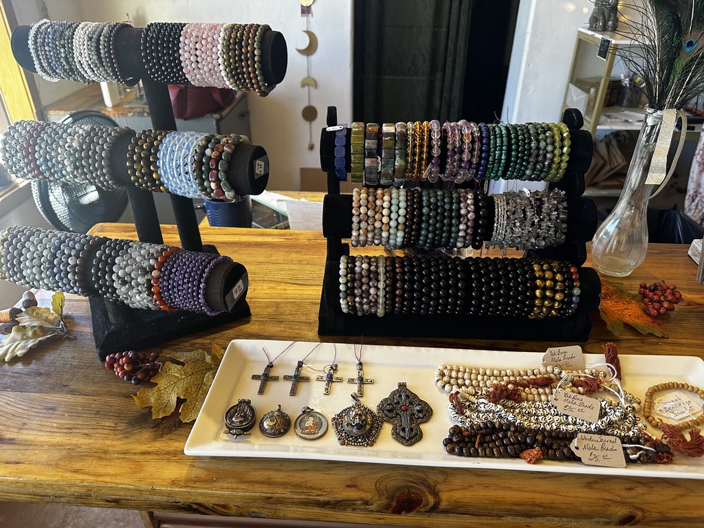 Stands of beaded stone bracelets and mala beads on a wooden table
